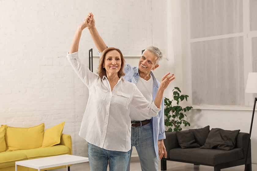 Happy senior couple dancing together in living room