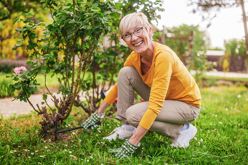 Happy senior woman gardening in her yard