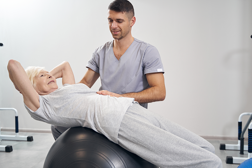 Senior female lying on exercise ball 
